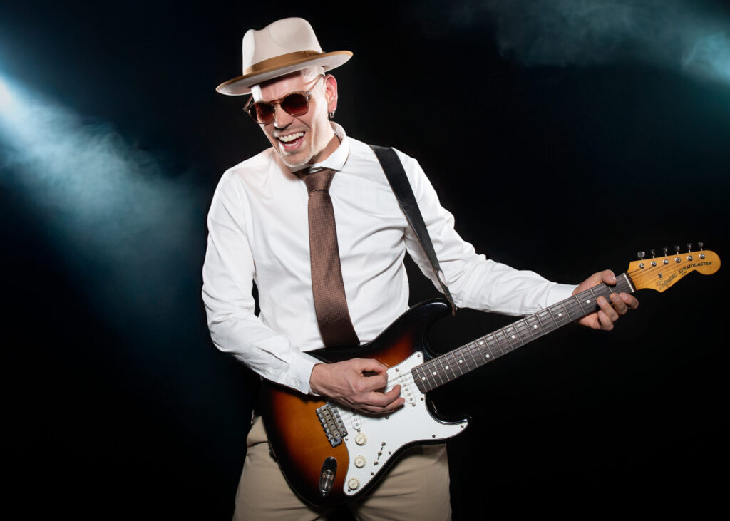 Sandy Leresche sourit en jouant de la guitare sur scène