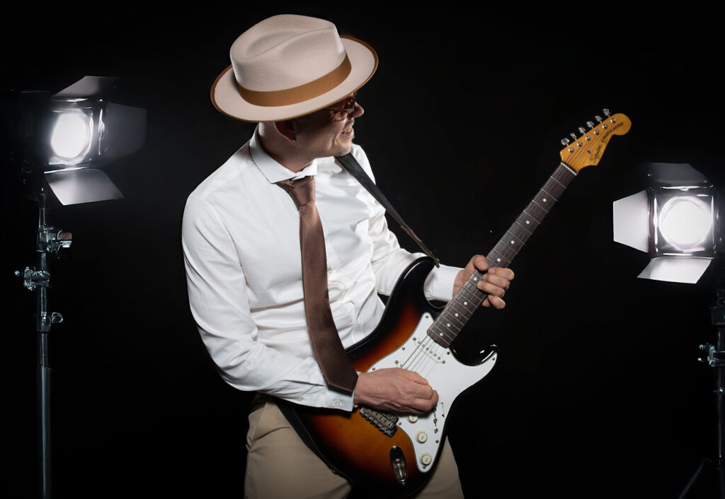 Sandy Leresche à la guitare entre deux projecteurs à volets