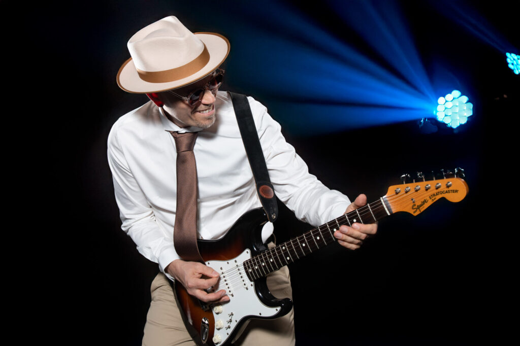 Sandy Leresche joue de la guitare sous des faisceaux bleus