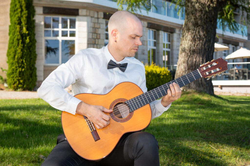 Sandy Leresche assis dans l'herbe avec sa guitare classique