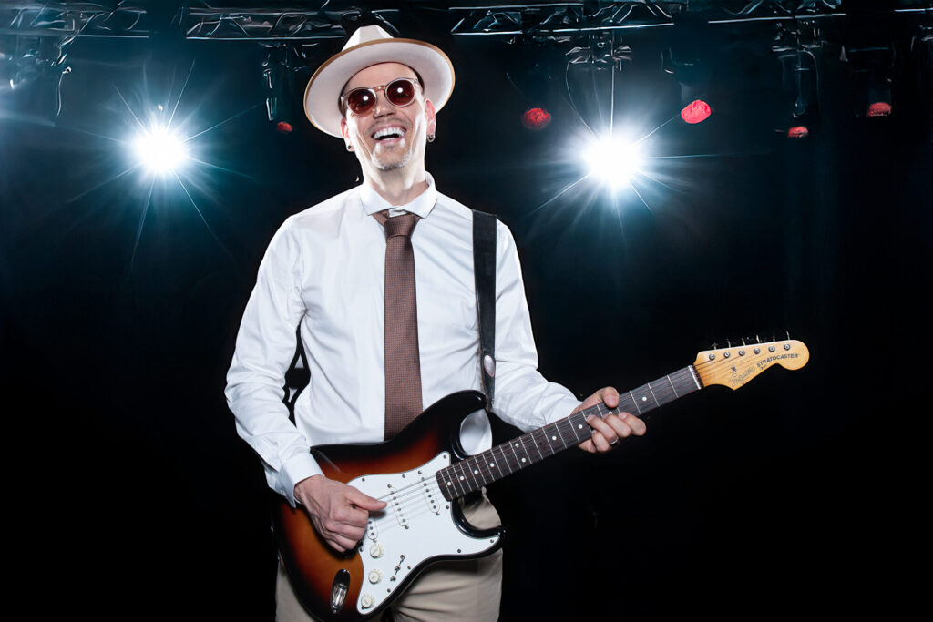 Sandy Leresche à la guitare électrique entre deux projecteurs de scène