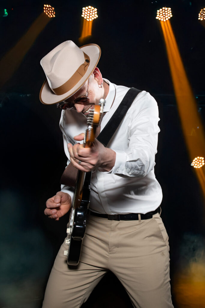 Sandy Leresche penché sur sa guitare sous des faisceaux orange